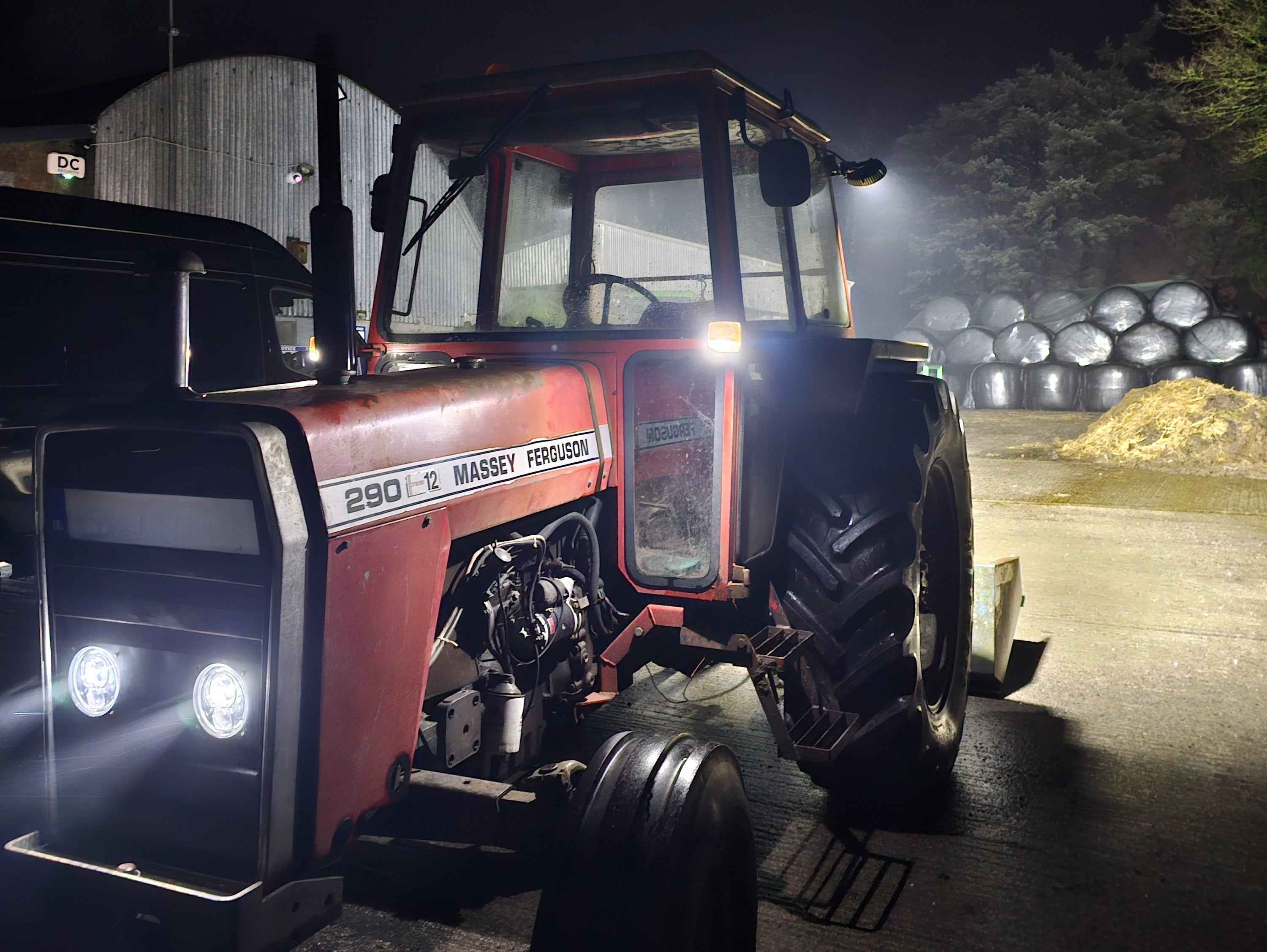 Red Massey Ferguson tractor with headlights on at night
