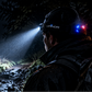 A person outdoors at night wearing a Luminor headlamp that casts a bright beam of light, with the Luminor brand name and logo displayed prominently on the left side of the image.